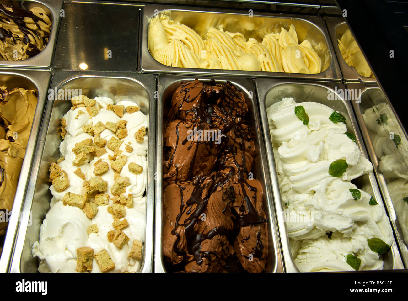 Stainless steel tubs of fancy gelatos in ice cream freezer display case at midtown farm market Stock Photo