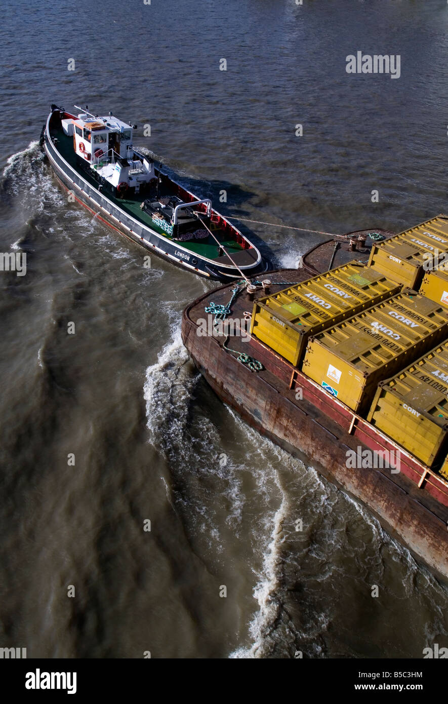 Tug boat pulling barges with recycling containers River Thames London UK Stock Photo