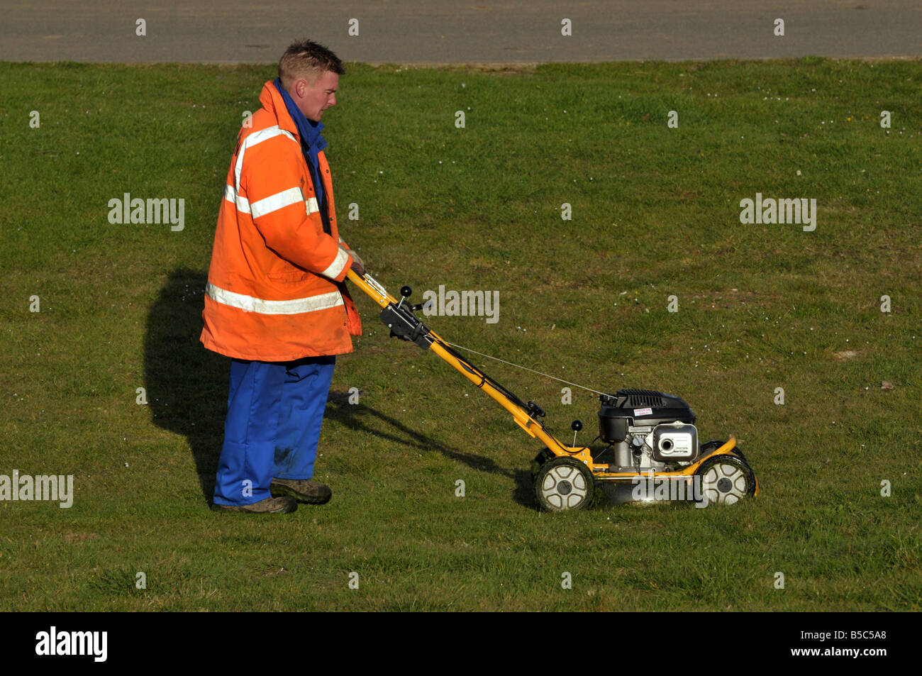 Man cutting grass with petrol mower Lincolnshire England UK Stock Photo