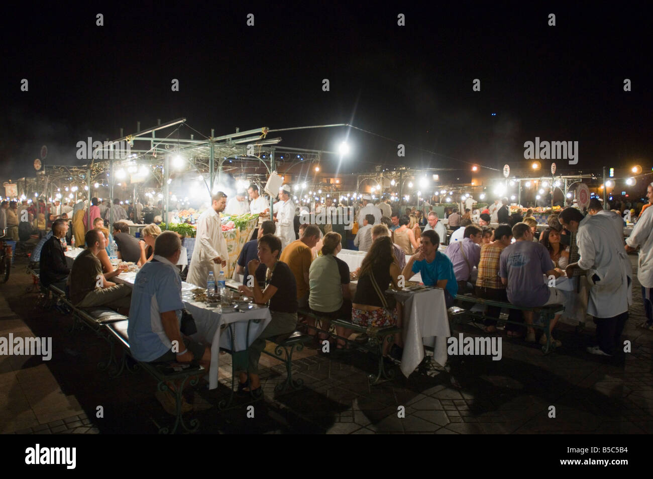 A view of the open air 'restaurants' at the Djemaa El Fna in Marrakesh at night with people eating. Stock Photo