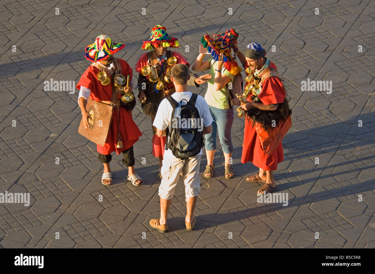 3 men in traditional dress as water carriers pose for a tourist camera at the Djemaa El Fna - the main market square of Marrakes Stock Photo