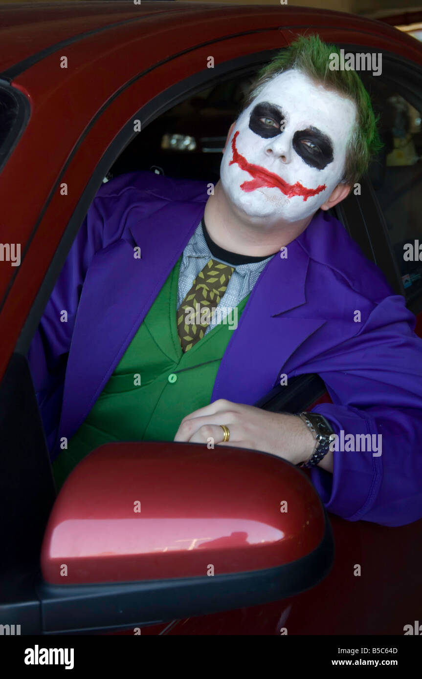 Young man made up as a scary clownish Halloween character in driver's seat of car Stock Photo