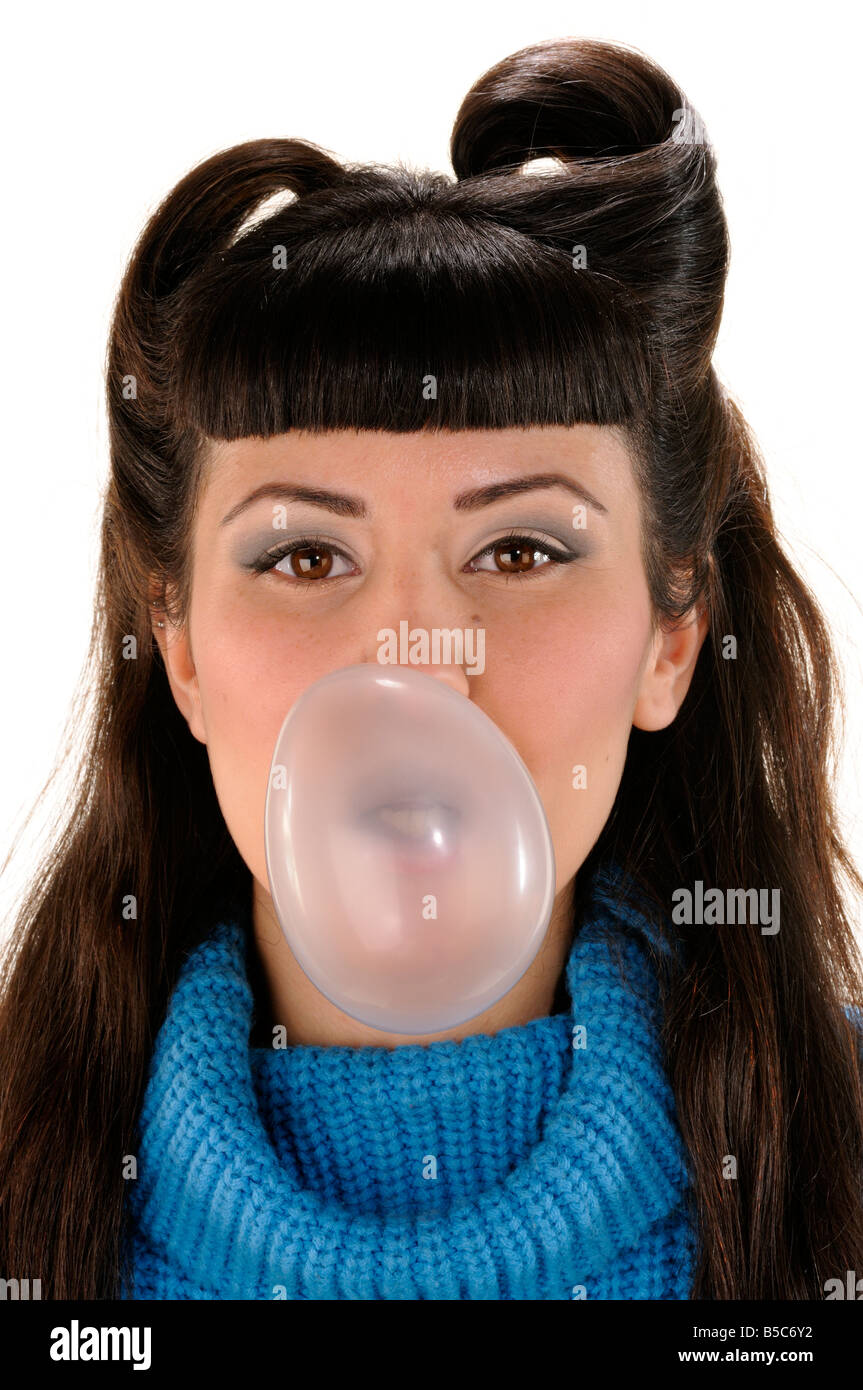 Young girl in long neck blue sweater blowing bubbles of a bubble gum Stock Photo
