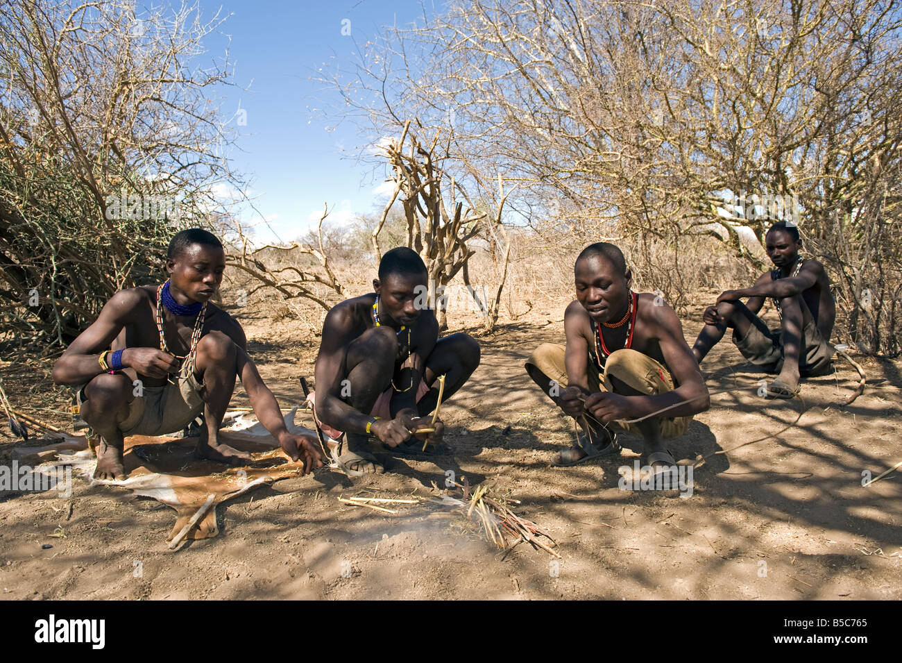 Hadza men bending a hunting arrow over a fire Lake Eyasi Tanzania Stock ...