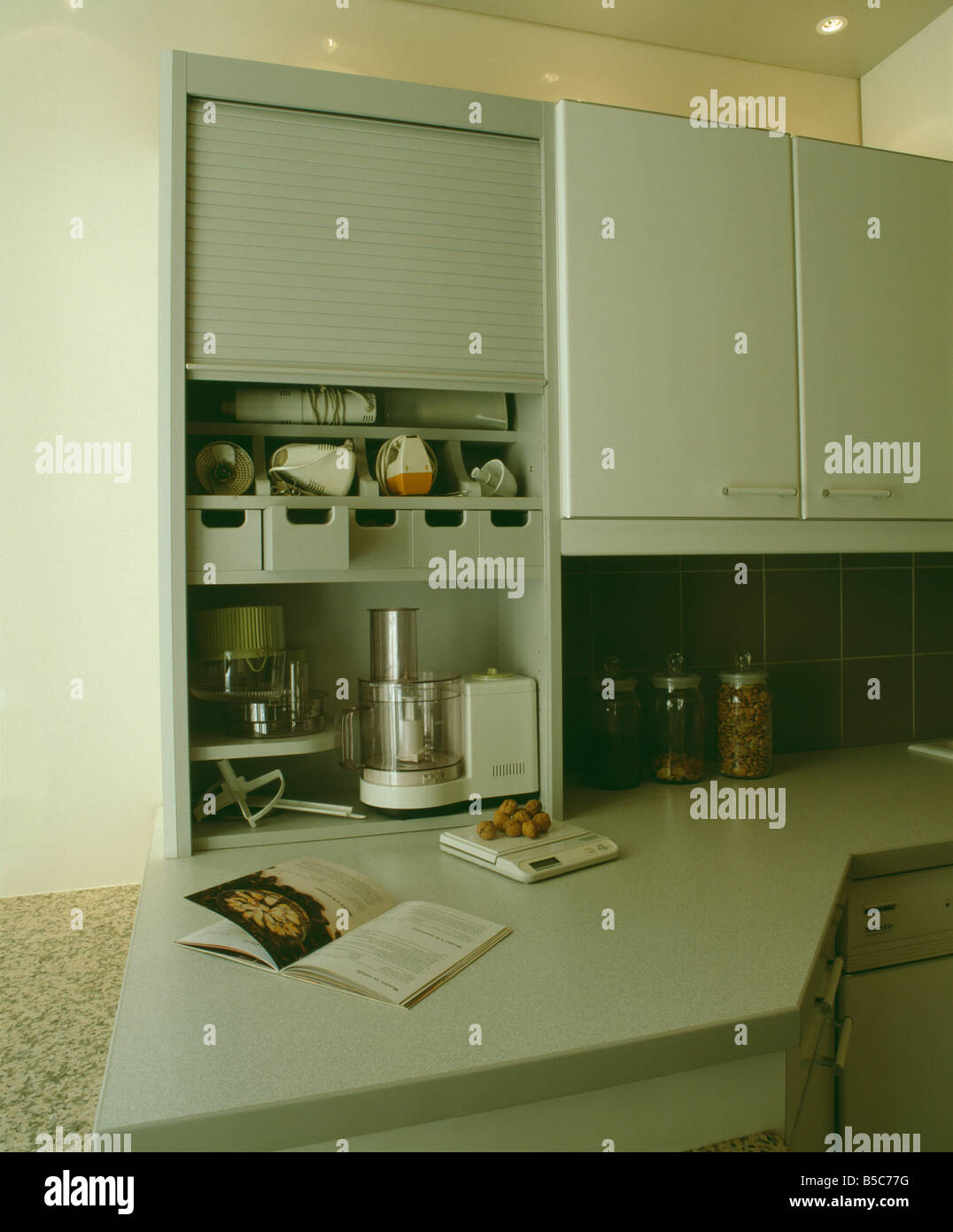 Electric food mixer and processor and storage shelves in kitchen unit with tambour shutter Stock Photo