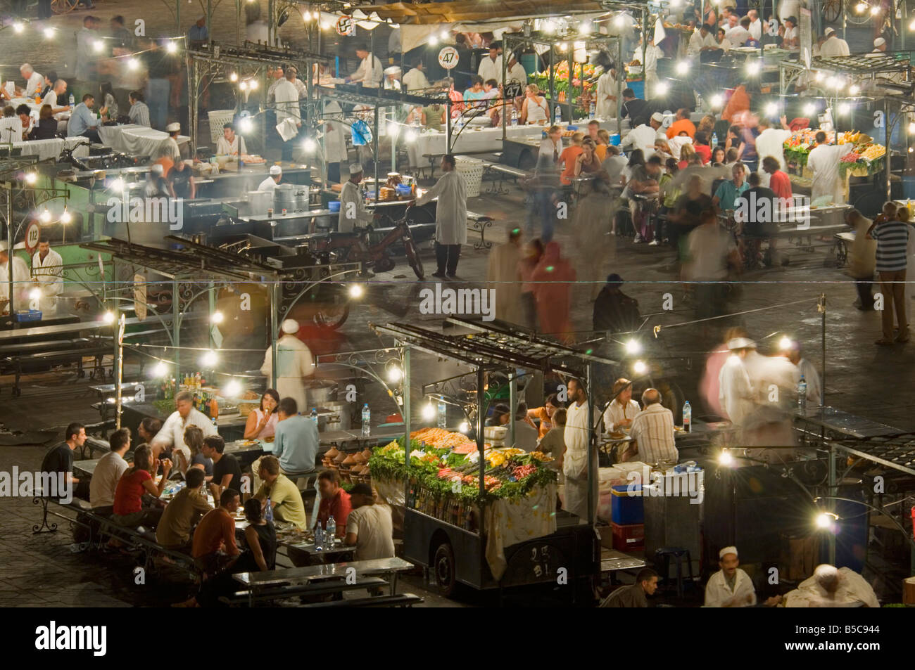 A compressed perspective aerial view of the open air 'restaurants' at the Djemaa El Fna with slow shutter speed for motion blur. Stock Photo