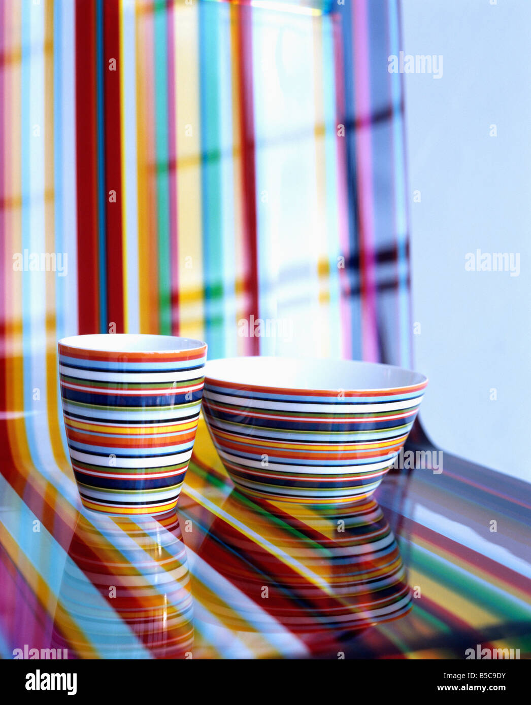 Close-up of multi-coloured striped bowl and cup on matching striped acrylic chair Stock Photo