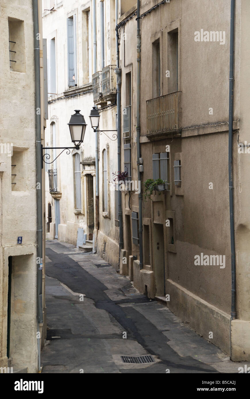A typical street in the old city of Montpellier with a narrow alley between sandstone buildings and old fashioned lanterns. Stock Photo