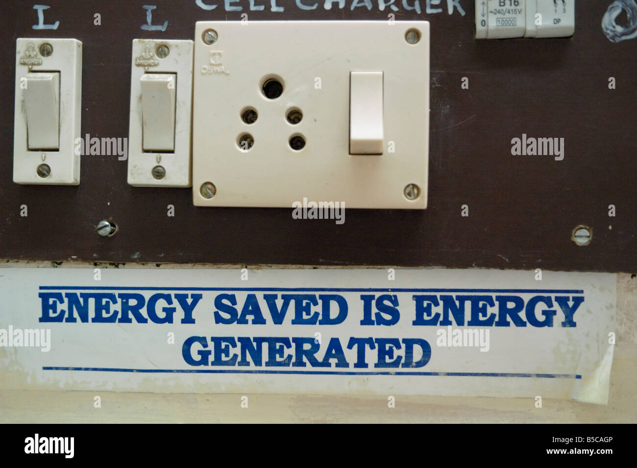 Electrical switches and socket in Ooty railway station with sign reading 'energy saved is energy generated'. Ooty, India. Stock Photo