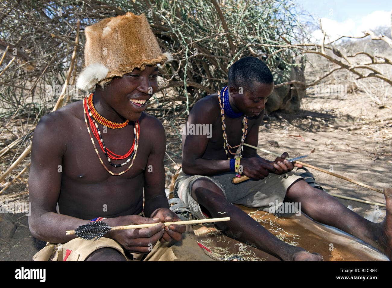 Members of the Hadza tribe preparing arrows for a hunt Lake Eyasi Tanzania Stock Photo