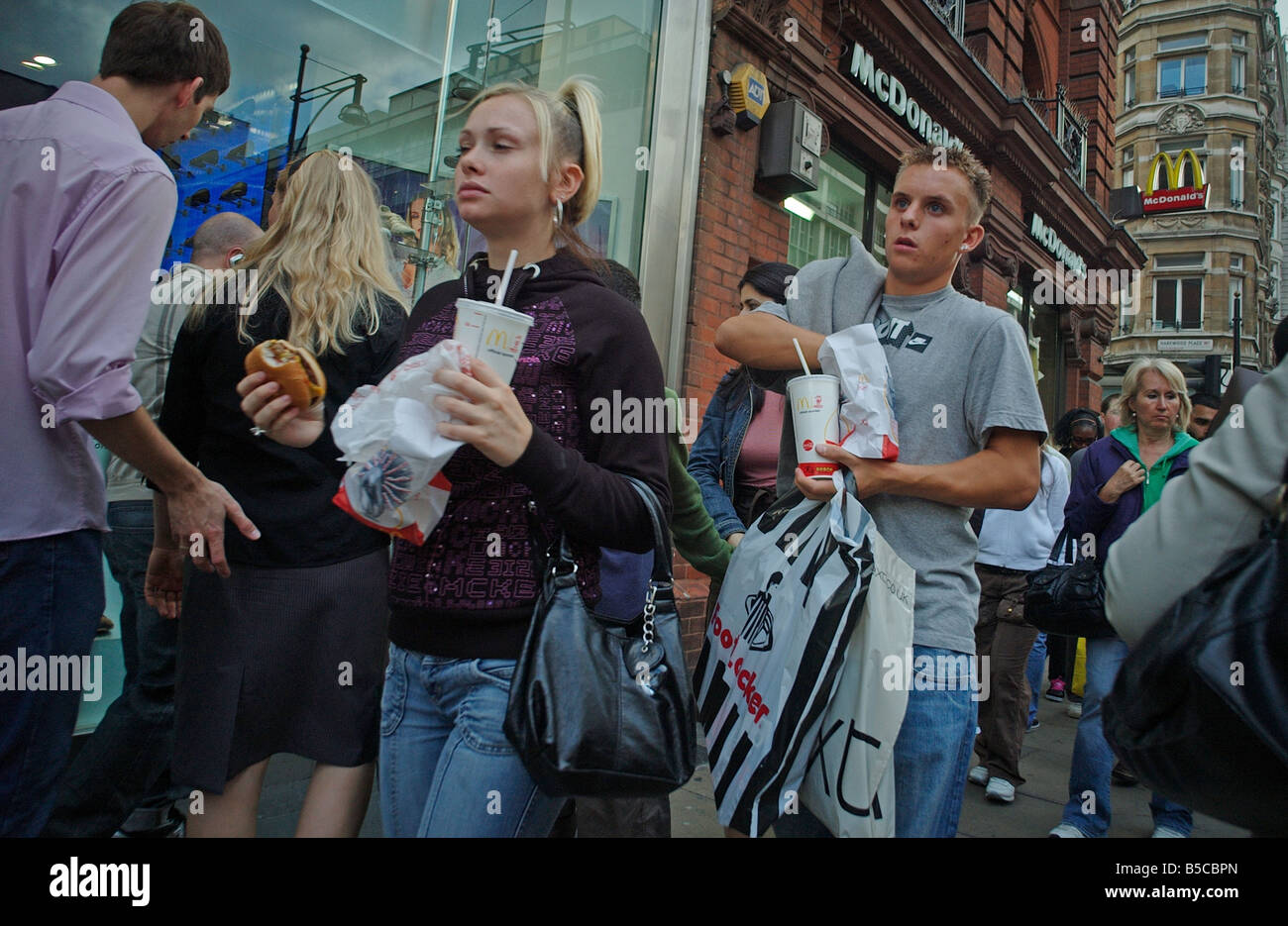 A couple walking down Oxford street eating Fast Food from  McDonalds Stock Photo