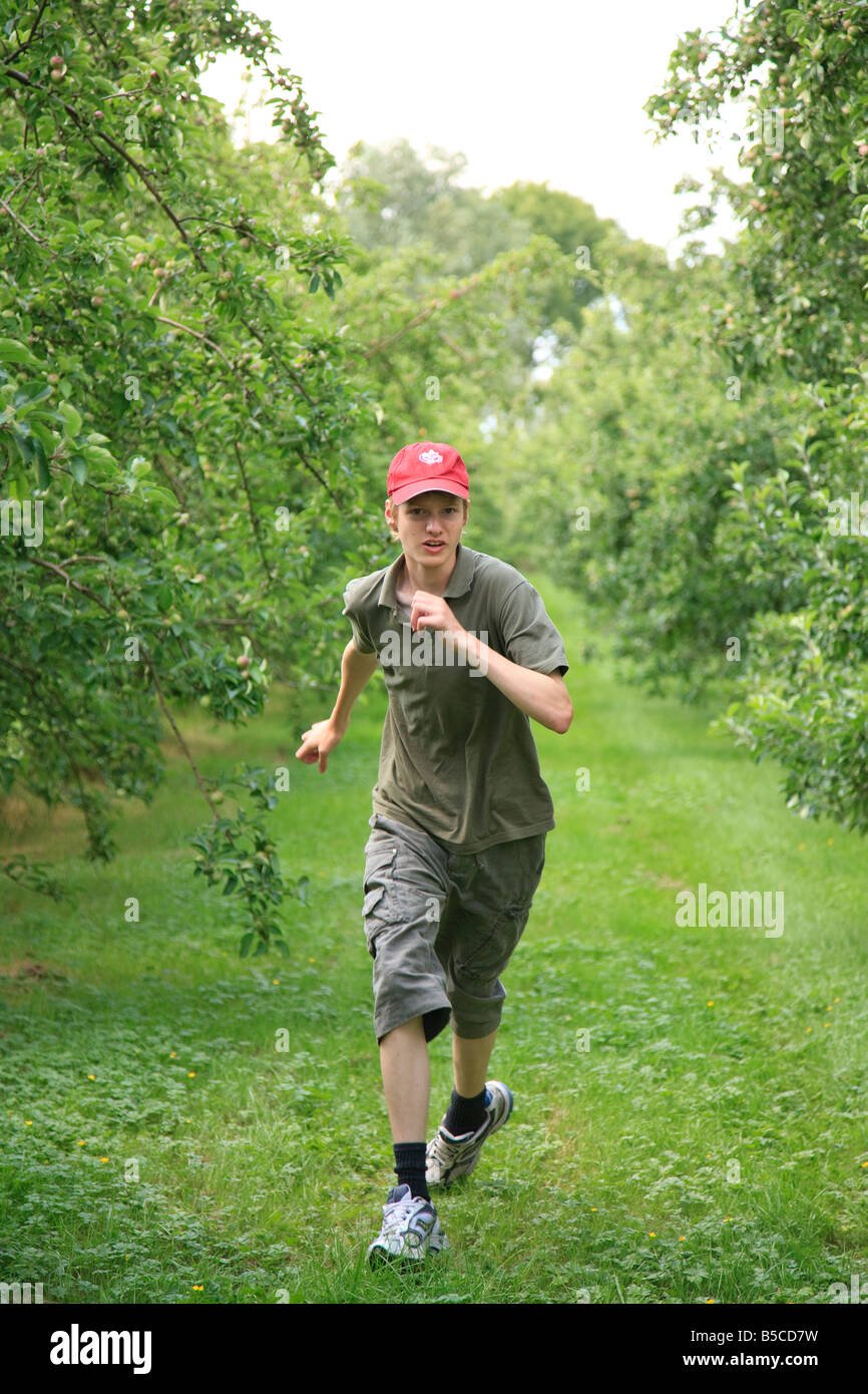 teenage boy 15 years old running in apple orchard Stock Photo