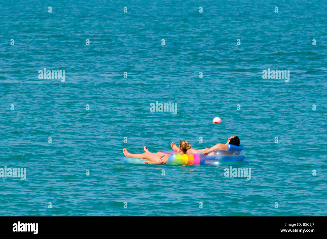 A couple on two lilos floating in the arabian ocean, Ras Al Khaimah UAE Stock Photo
