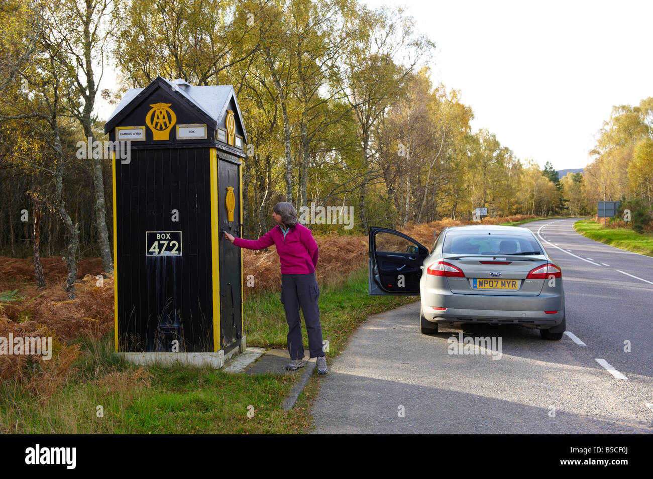 Woman opening door to AA phone box Scotland UK Stock Photo