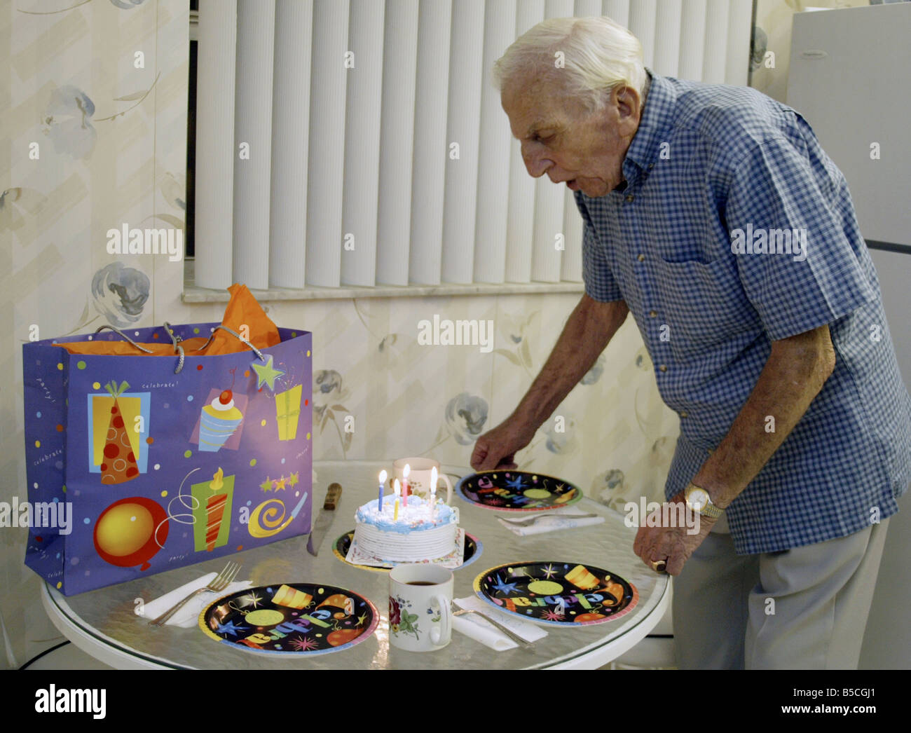 Senior citizen blowing out candles on a birtday cake Stock Photo