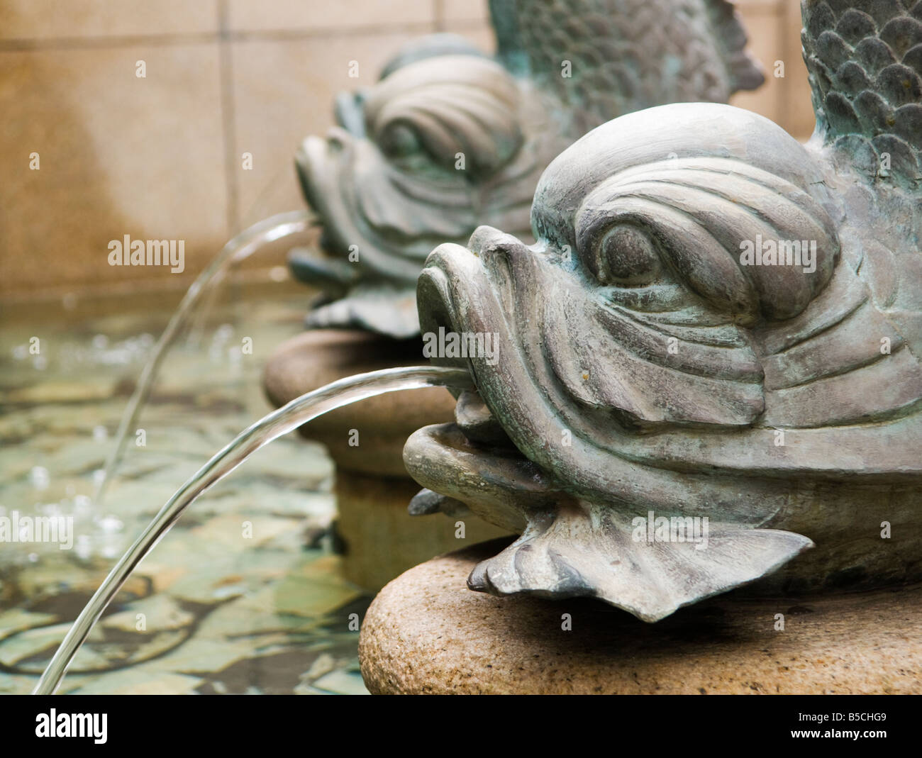 'Bronze carp fish fountains spray water into an ornate pond in a public courtyard in Hong Kong.' Stock Photo