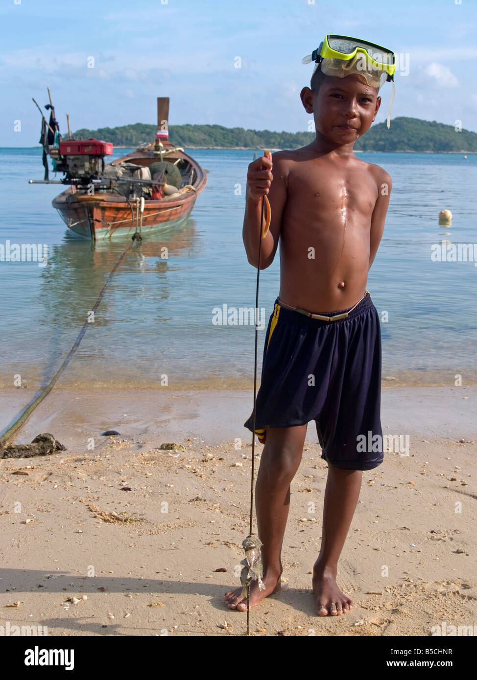 young sea gypsy fisherman and his speared squid on Rawai Beach in