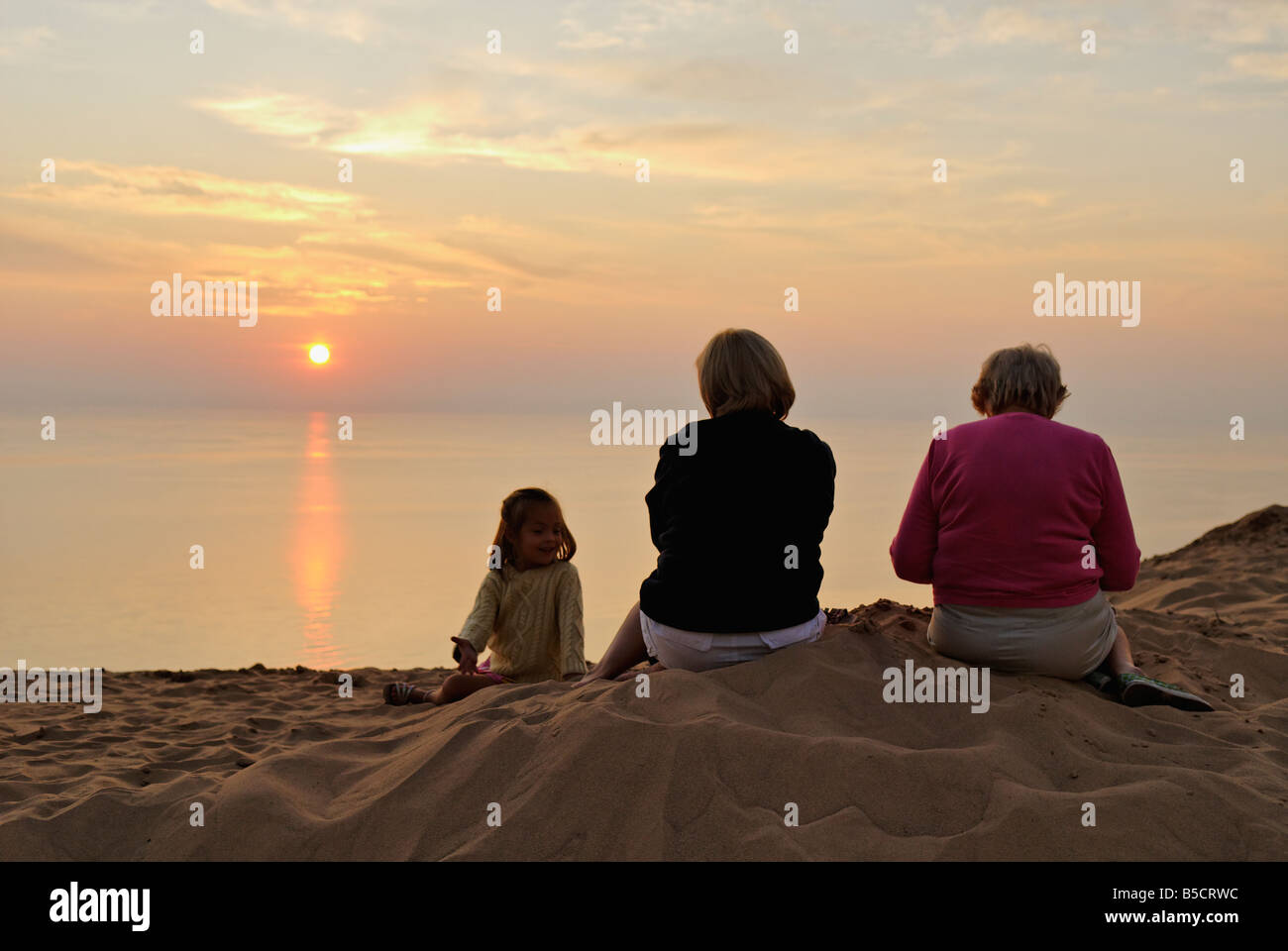 Mother Daughter and Grandmother Watching Lake Michigan Sunset from Sand Dune at Sleeping Bear Dunes National Lakeshore Michigan Stock Photo