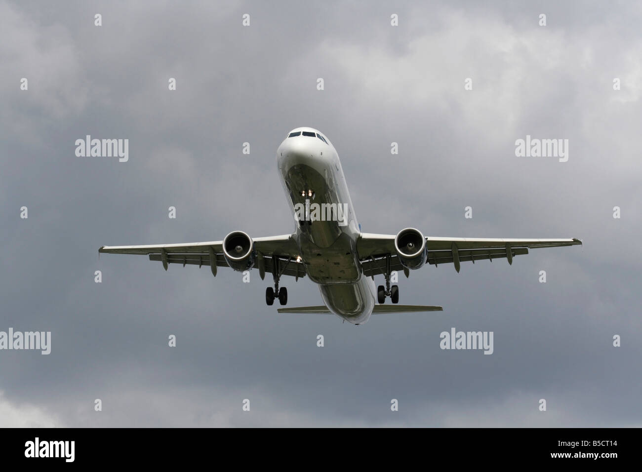 Air travel. Airbus A321 commercial airliner arriving in a cloudy sky. Front view with no livery and proprietary details deleted. Modern aviation. Stock Photo