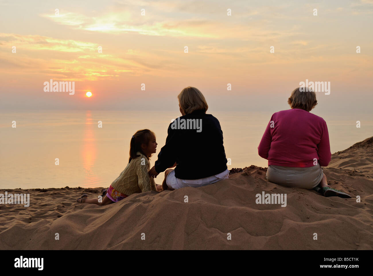 Mother Daughter and Grandmother Watching Lake Michigan Sunset from Sand Dune at Sleeping Bear Dunes National Lakeshore Michigan Stock Photo