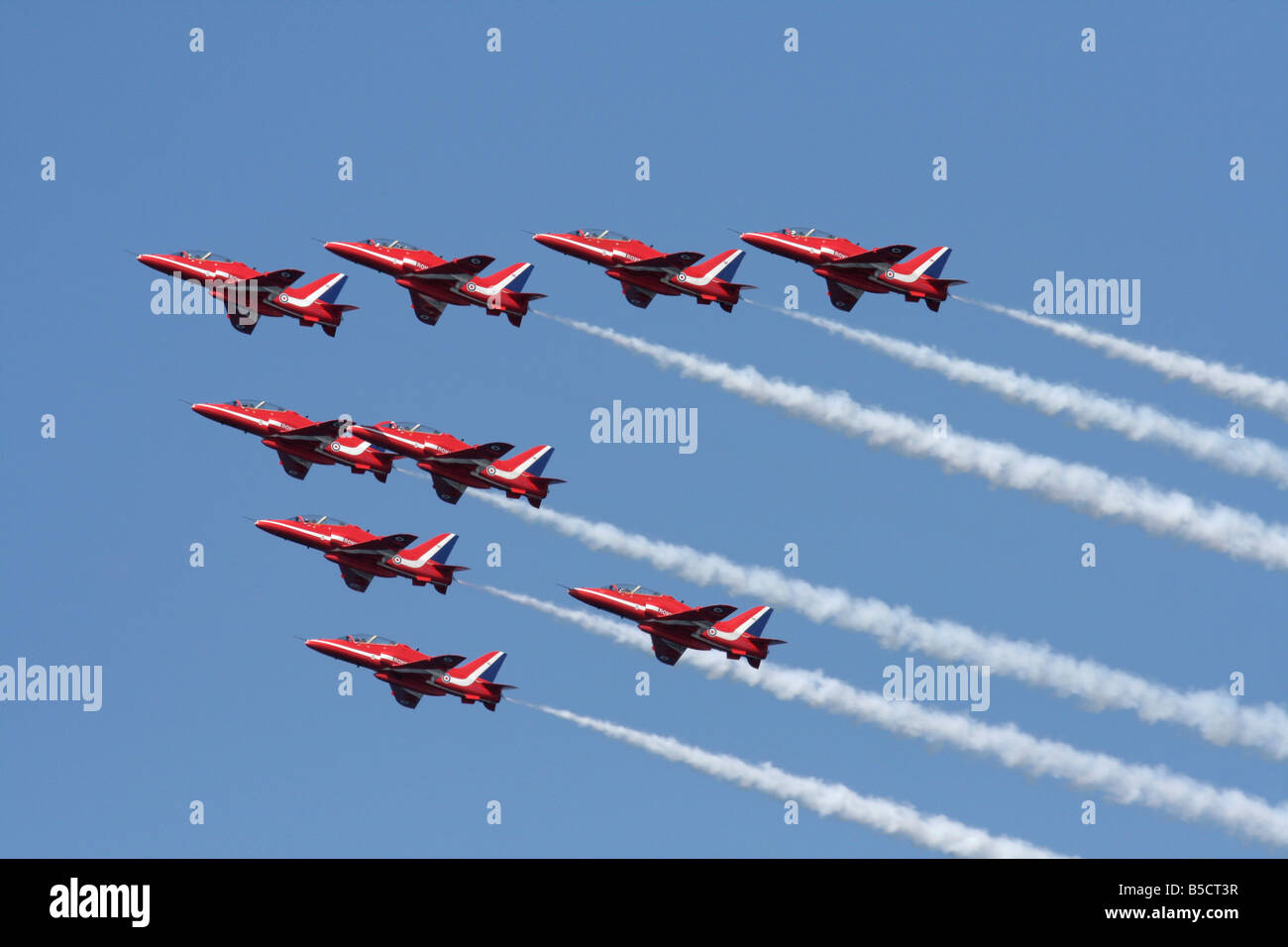 The Royal Air Force Red Arrows aerobatic team flying in formation and generating smoke trails Stock Photo