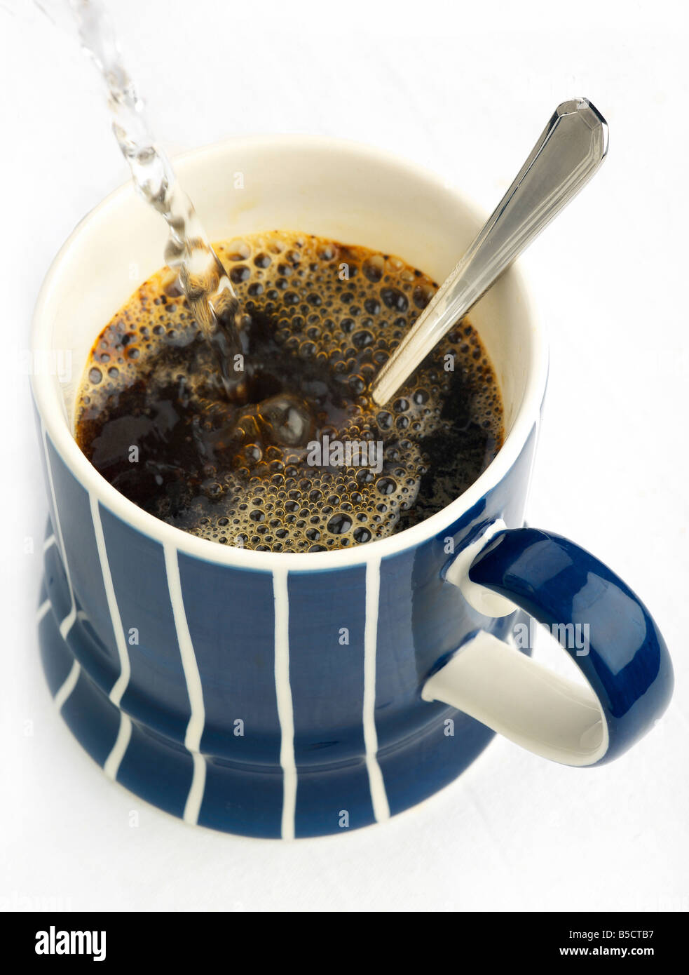 A steaming mug of instant coffee with hot water being poured Stock Photo