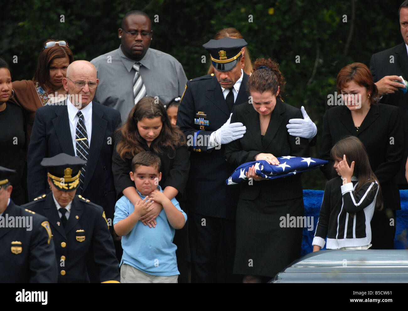 A Police funeral with the family mourning after receiving the flag from the officers coffin from the color guard Stock Photo