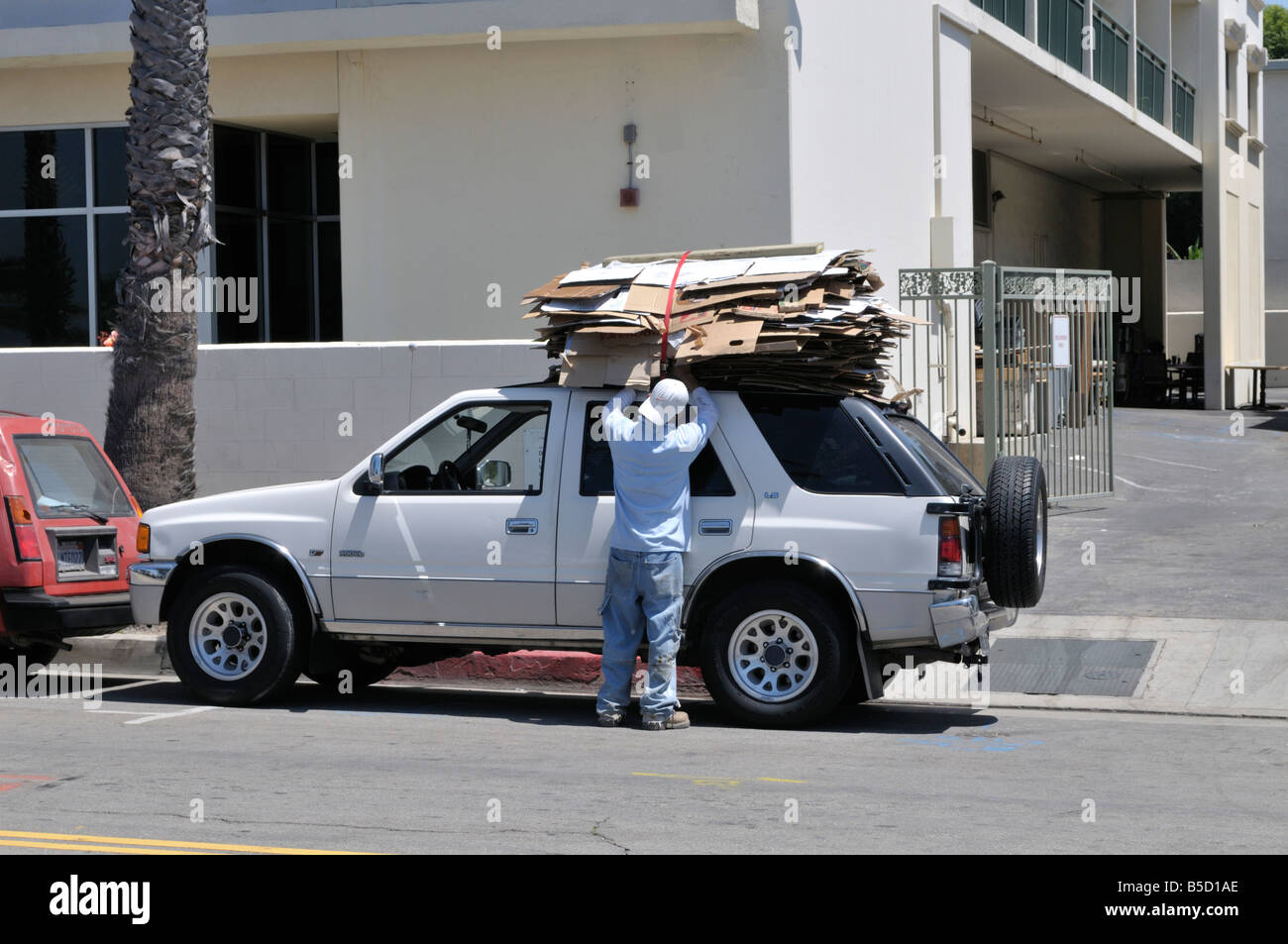 Young man loading a heap of packaging material on top of his vehicle Stock Photo