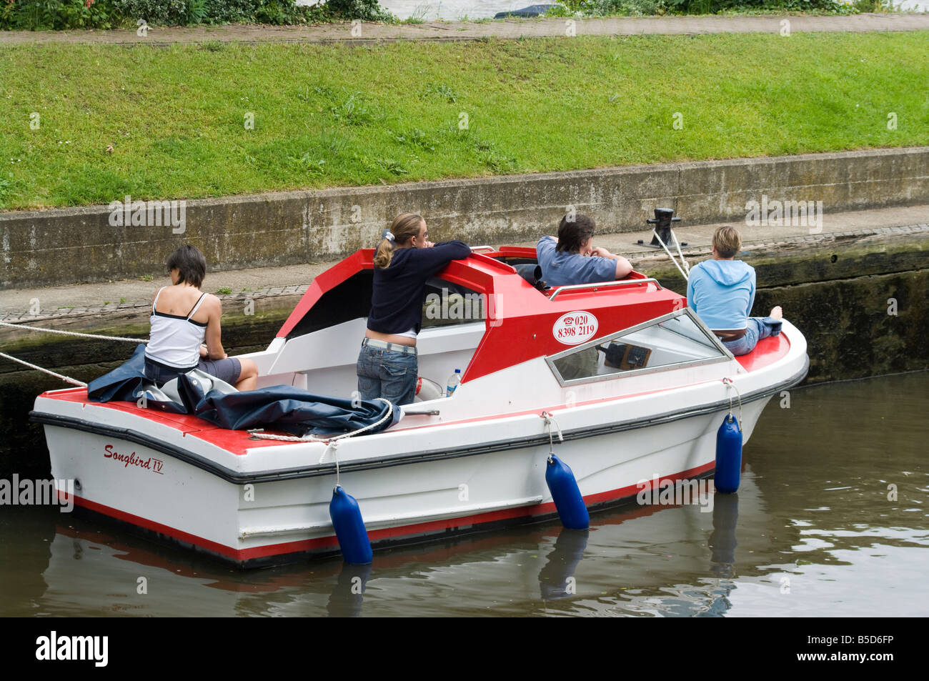 Motorboat Hire Boat with teenagers teenage friends on Boating Day Out in Molesey Lock on the River Thames Molesey Surrey Stock Photo