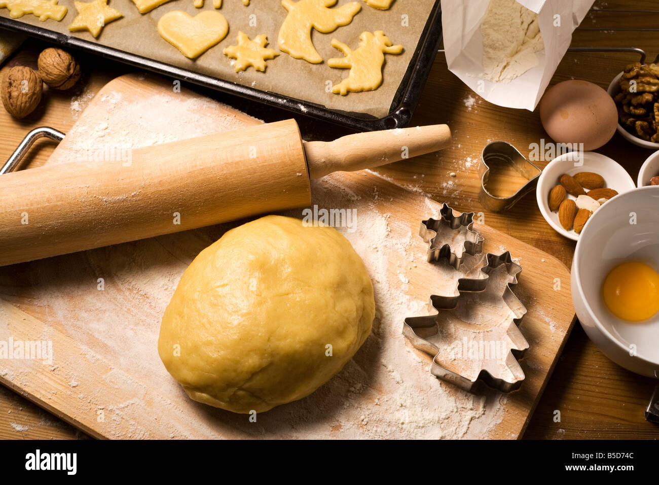 home baking scene - dough, raw christmas cookies on oven rack, various baking ingredients and utensils Stock Photo