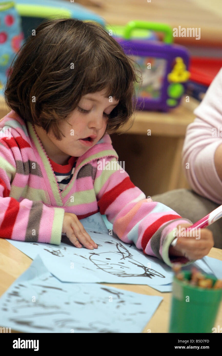 A young girl draws at pre-school nursery. Stock Photo