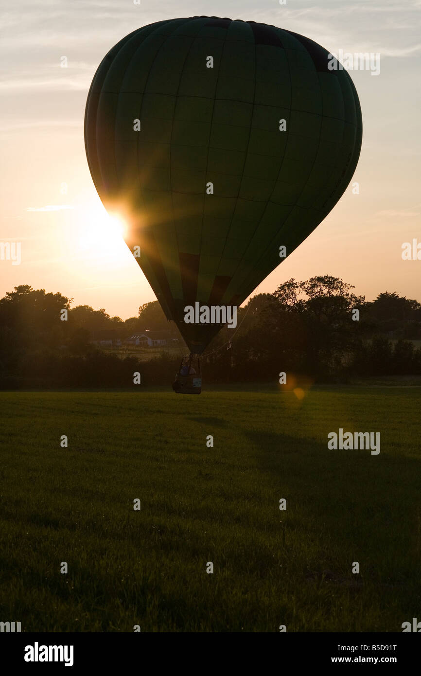 Hot air balloon landing in a field at sunset Stock Photo