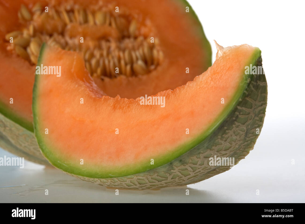 cut half of ripe european cantaloupe melon showing seeds with individual slice with seeds removed Stock Photo