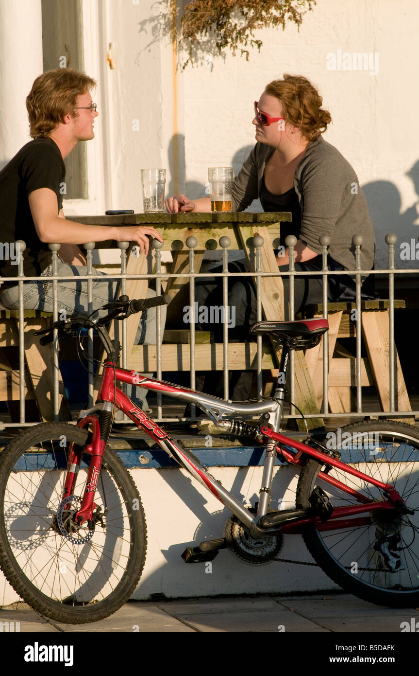 Young couple drinking beer outside bar on a summer evening Aberystwyth