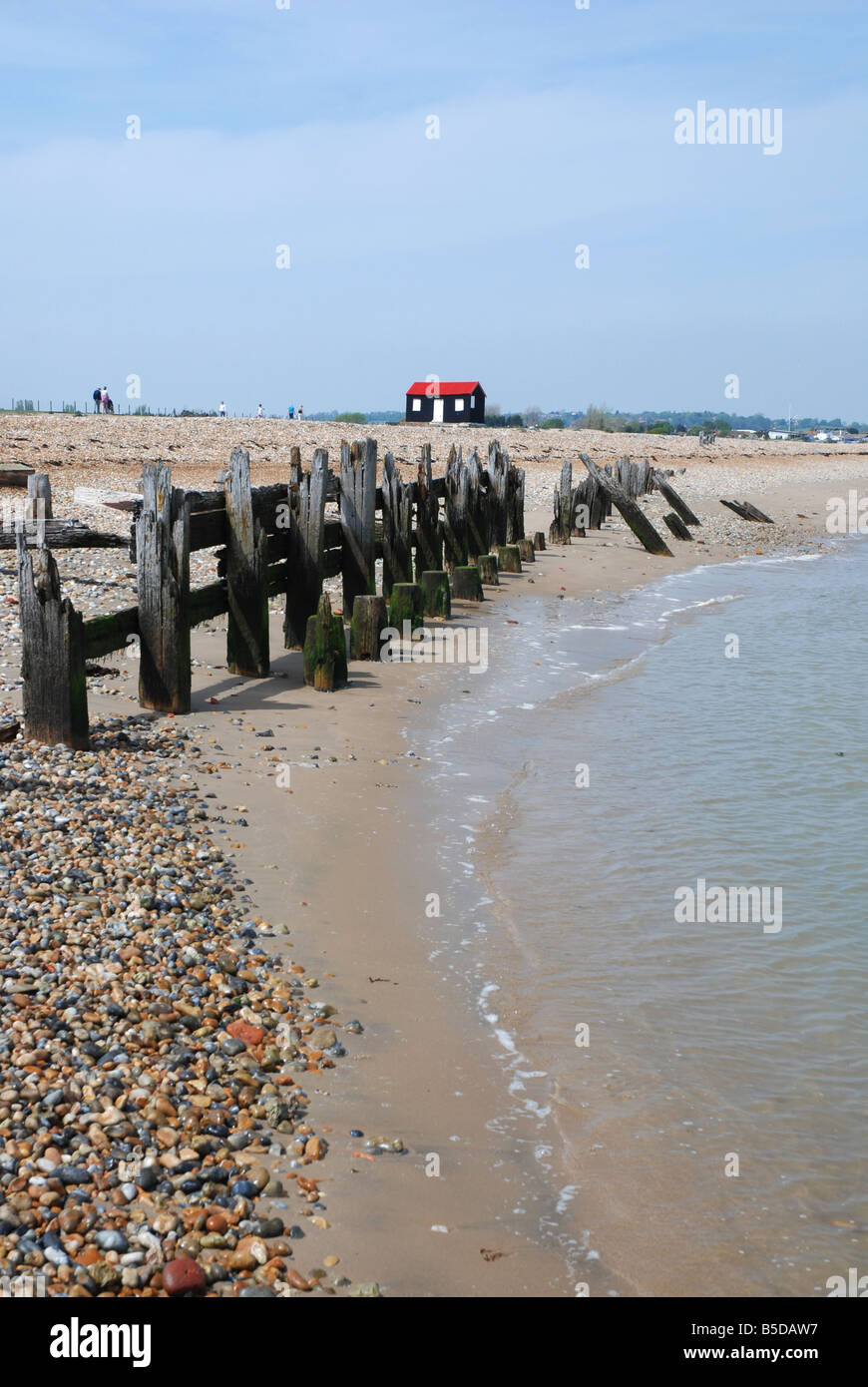A portrait photograph of a raggedy old wooden beach fence at the water's edge of Rye Harbour Nature Reserve. Stock Photo