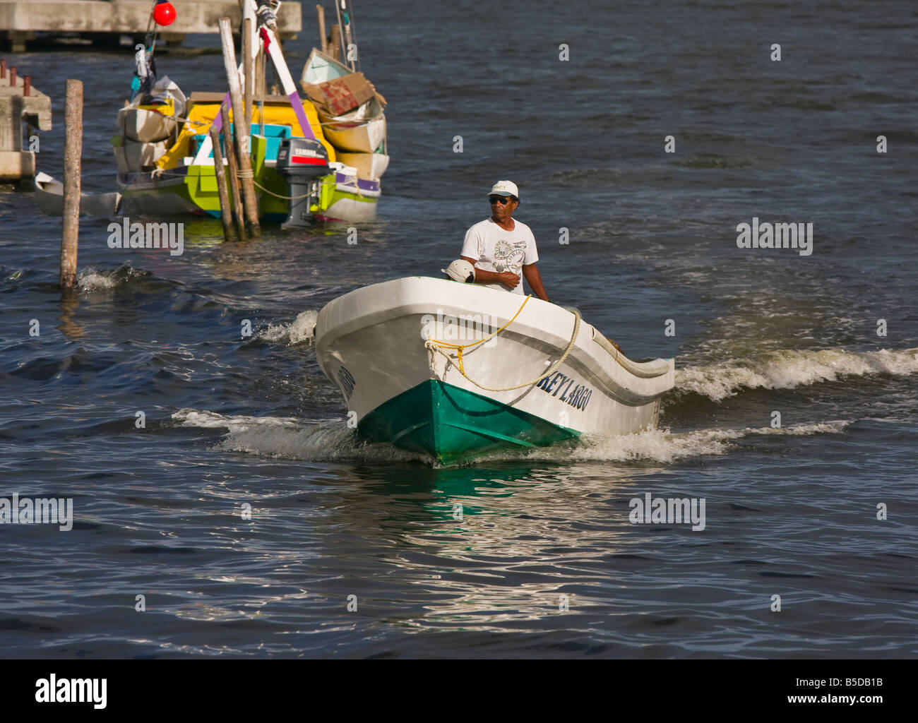 BELIZE CITY BELIZE Man pilots small boat in Belize Harbor at the mouth of Haulover Creek Stock Photo