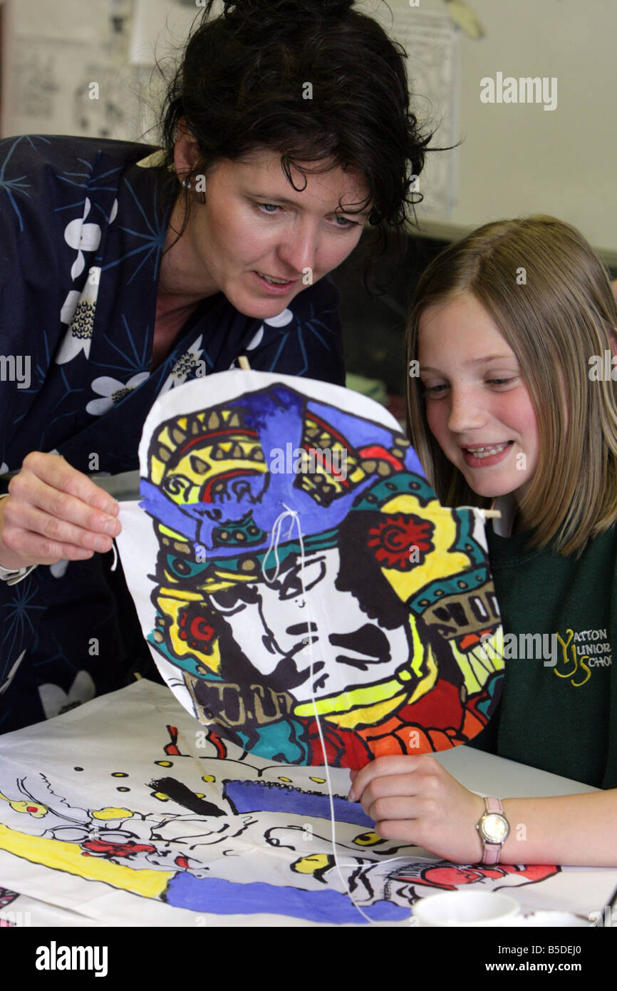 A teacher looks at a mask made by a pupil during an art lesson. Stock Photo