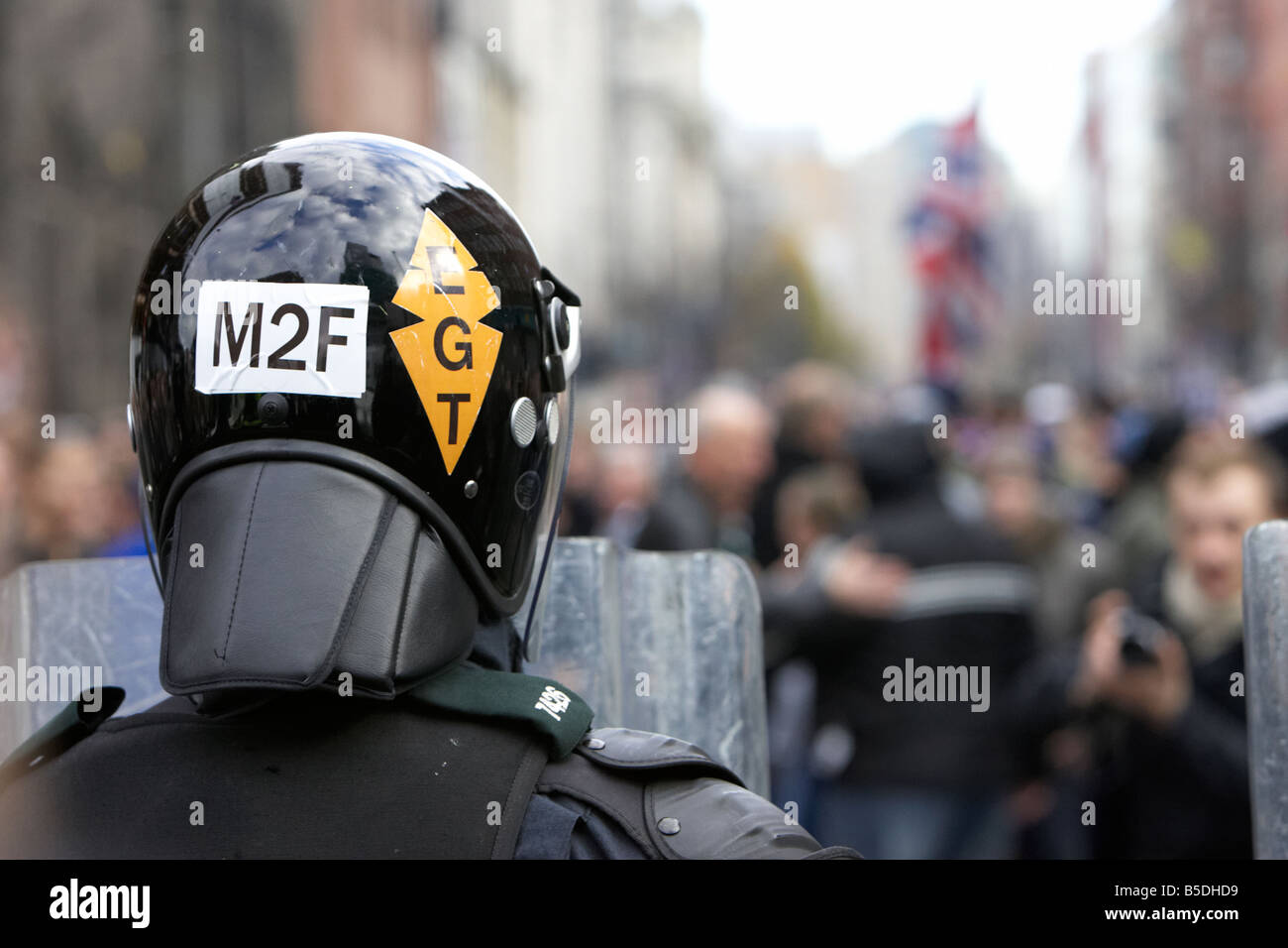PSNI Police Service of Northern Ireland riot control officer stands guard with helmet and riot shield during loyalist protest Stock Photo