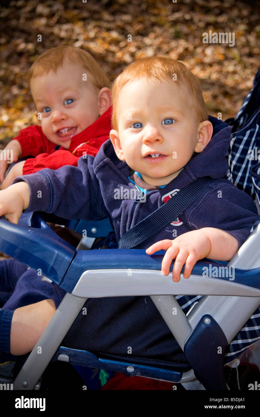 Twin brothers with red hair sitting in stroller outside Stock Photo