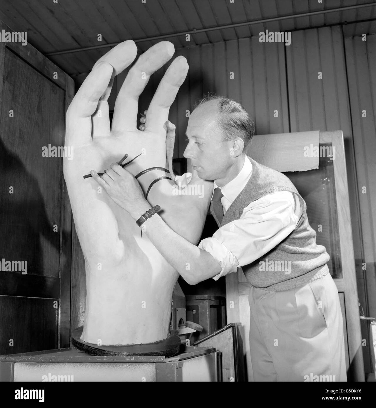 The workshop of a Midlands plastic figure factory, which manufacture a wide range of products from Puppets used in fairground amusements to shop mannequins. Our picture shows one of the craftsmen adding a few final touches to a hand which is bound for a shop diplay. January 1954 Stock Photo