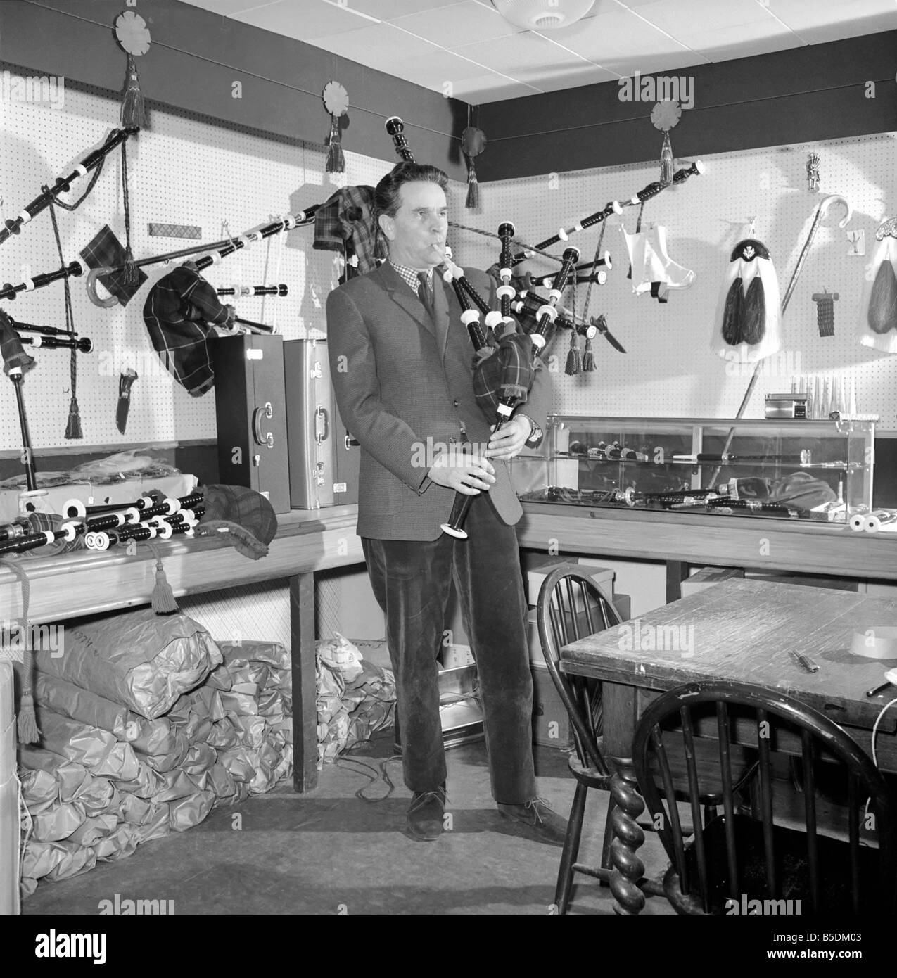 Bagpipe maker Mr. George Alexander seen here in his workshop. Circa 1960 Seen here playing a set of bagpipes he had manufactured Stock Photo