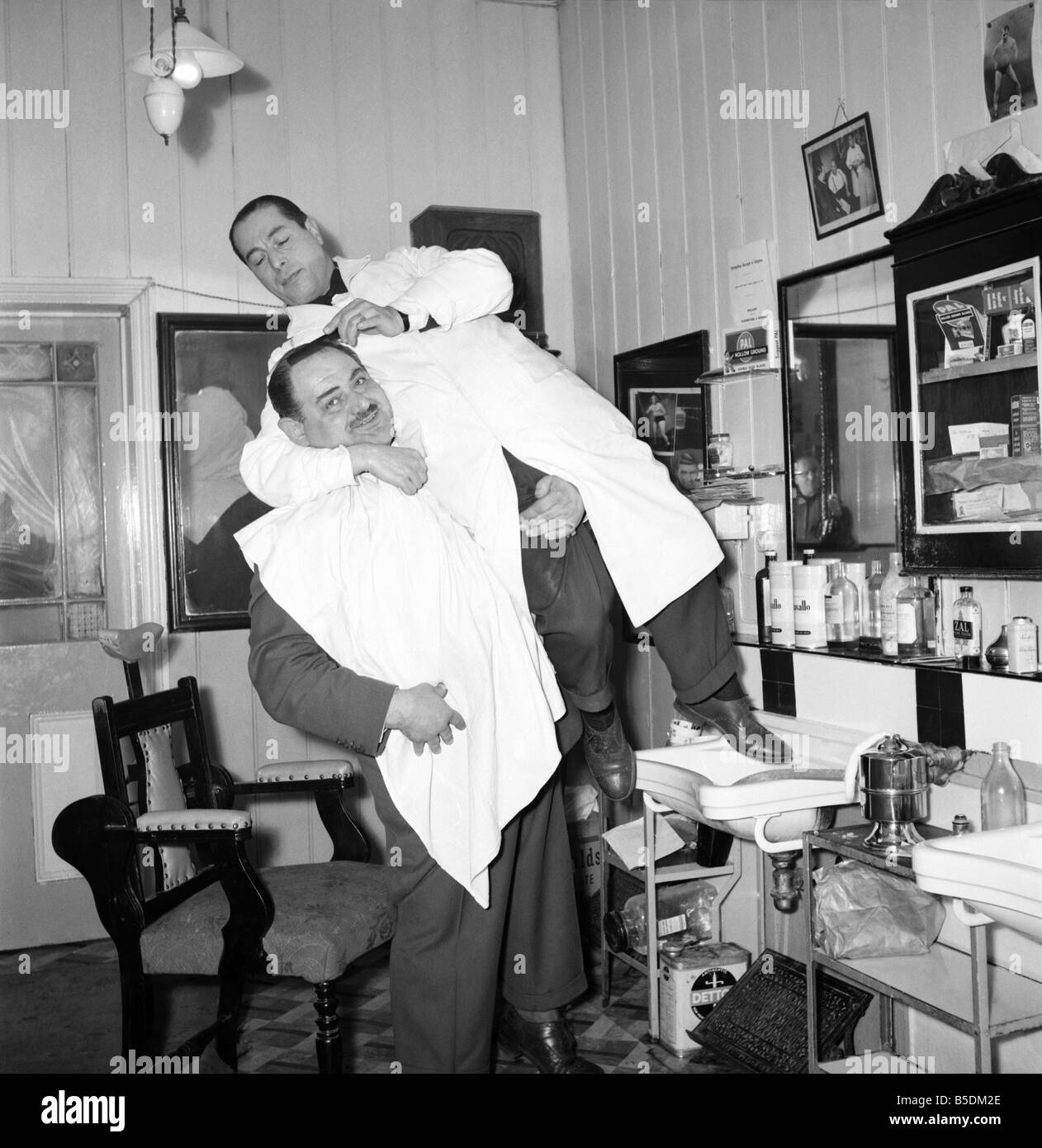 Mens Barbers Shop: Mr. Thomas the barber seen here having a joke with some of his customers. Circa 1957 Stock Photo
