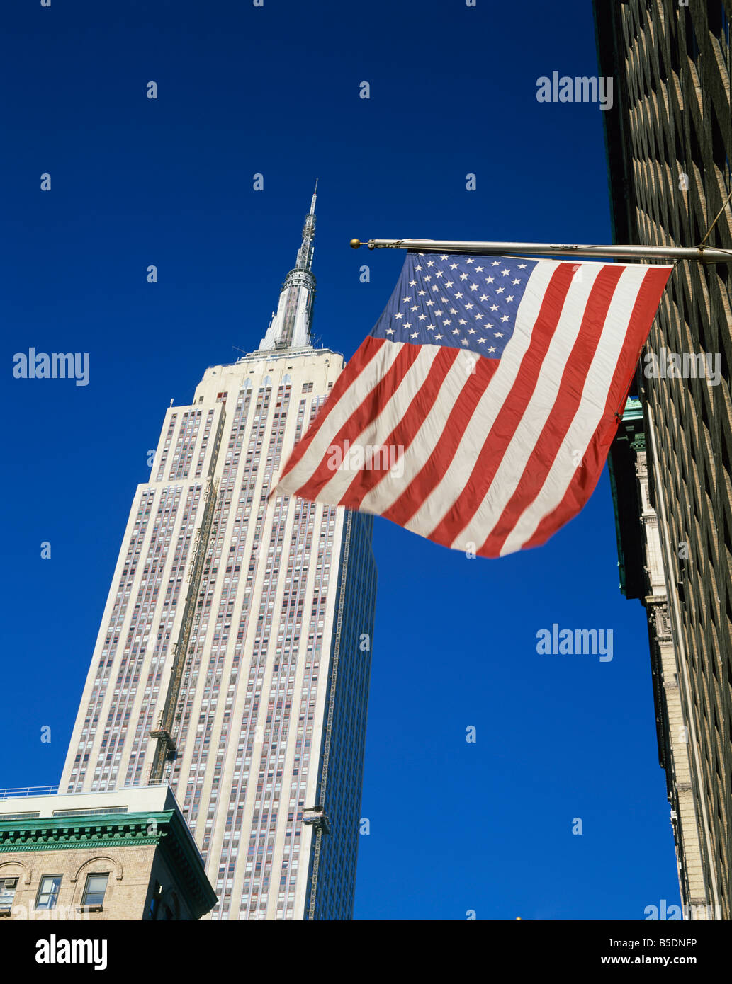 The American flag, the stars and stripes in front of the Empire State Building in New York, USA Stock Photo