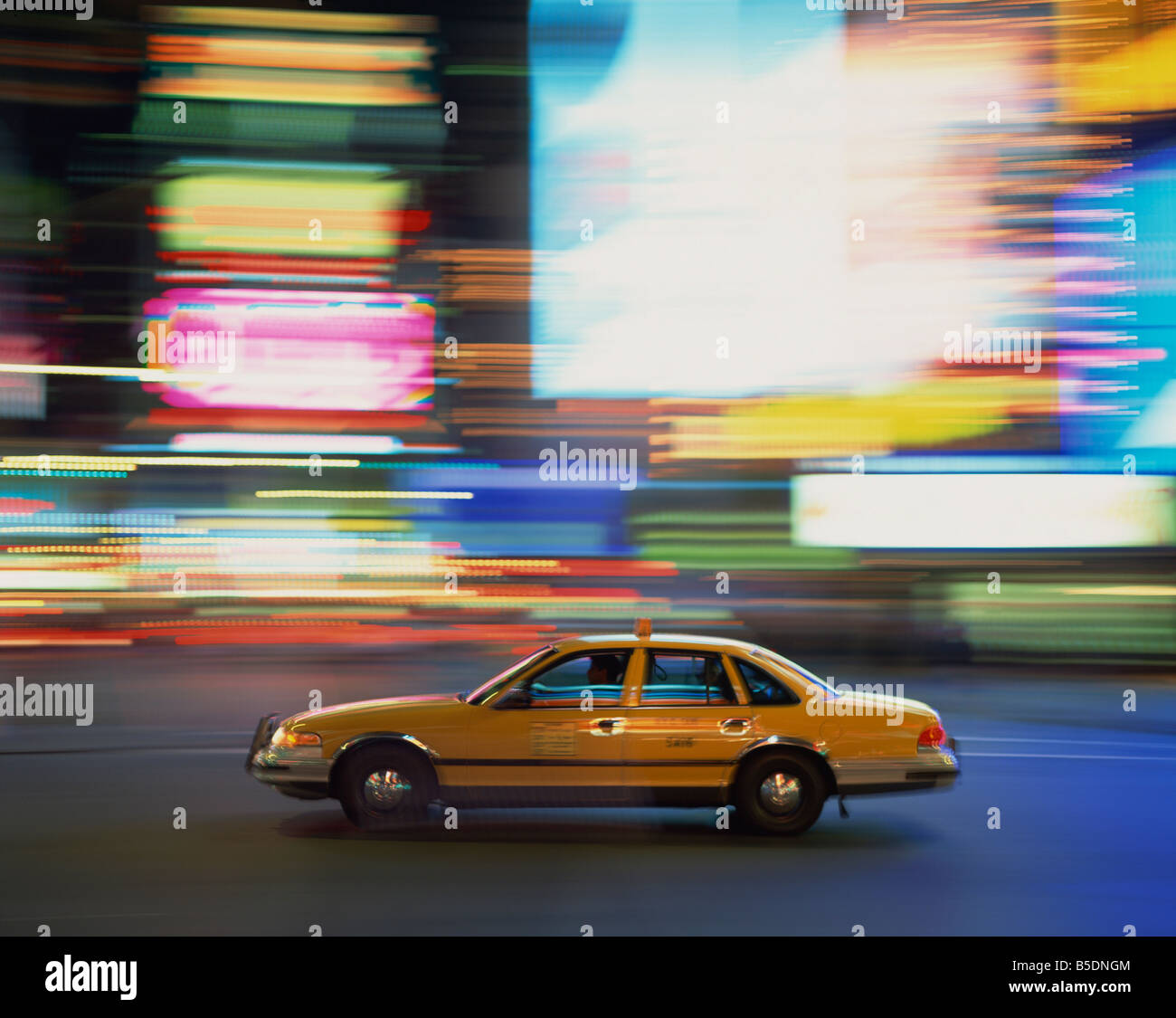 Yellow cab driving past blurred neon lights at night in Times Square in New York United States of America North America Stock Photo