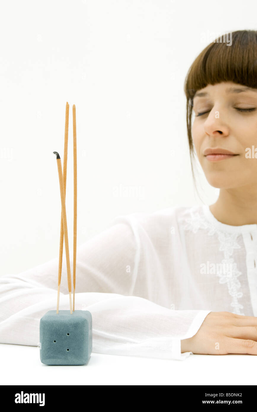 Woman sitting near incense, eyes closed Stock Photo