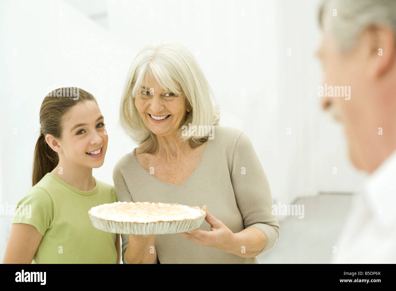 Grandmother and granddaughter side by side, senior woman holding pie Stock Photo