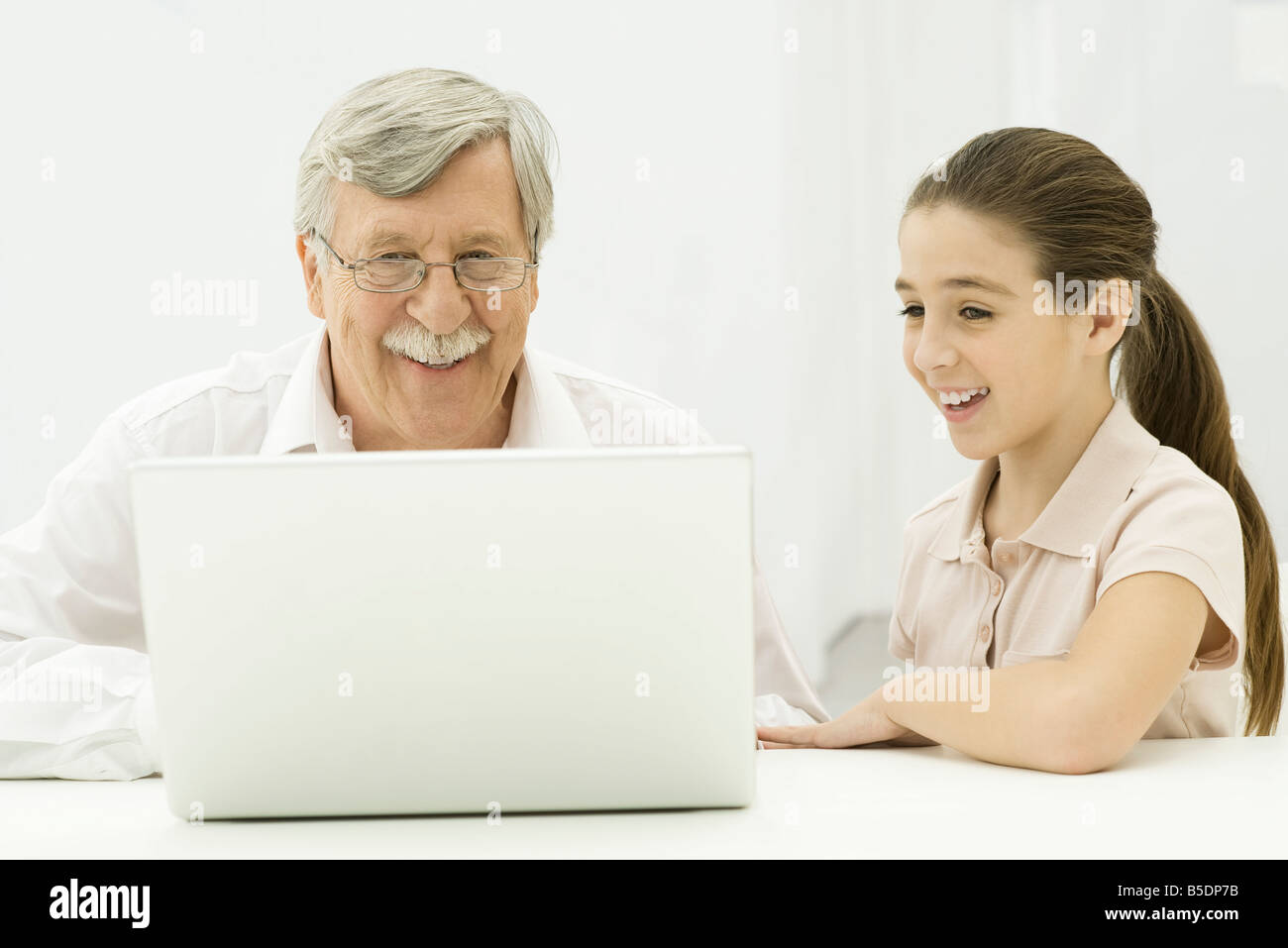 Grandfather and granddaughter looking at laptop together Stock Photo