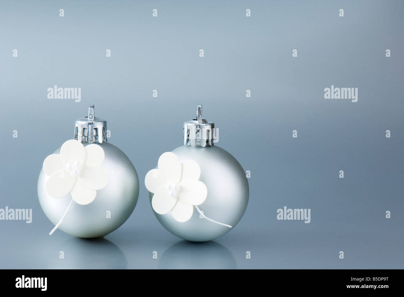 Two silver Christmas tree ornaments decorated with white flowers Stock Photo