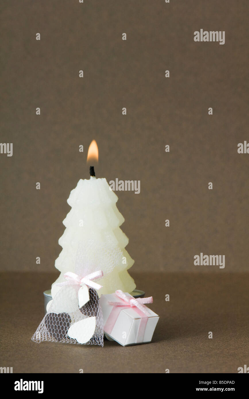 White Christmas tree shaped candle with miniature gifts set at base Stock Photo