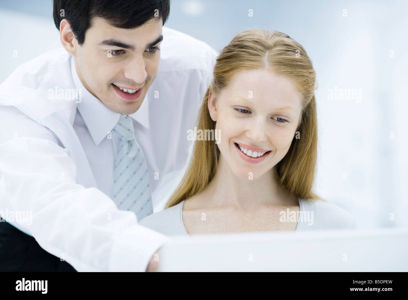 Professional man looking over female colleague's shoulder, pointing at laptop computer Stock Photo